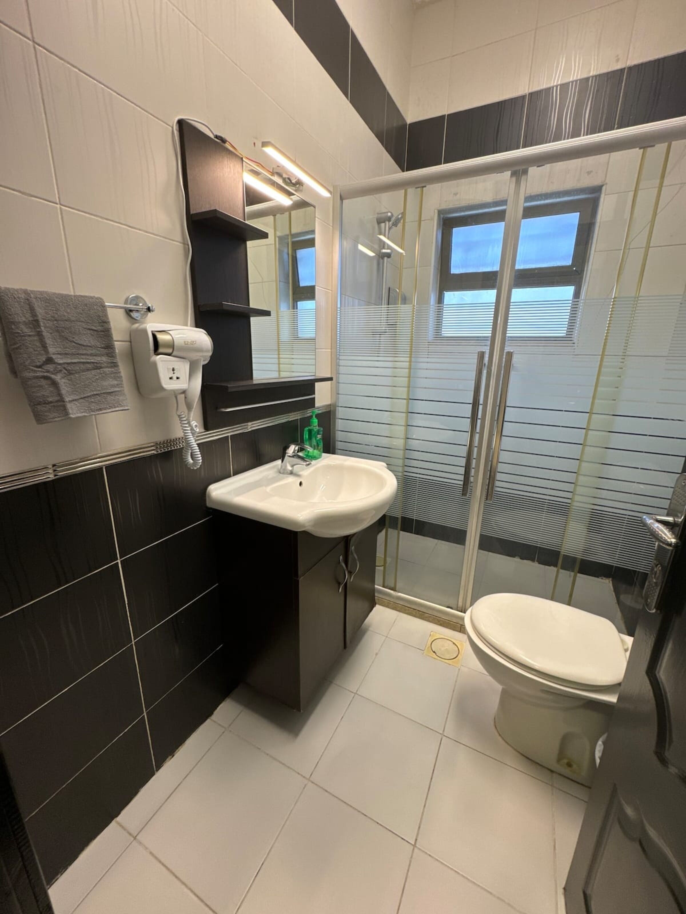 Une salle de bain moderne avec un lavabo blanc, un miroir, un porte-serviettes et une cabine de douche.