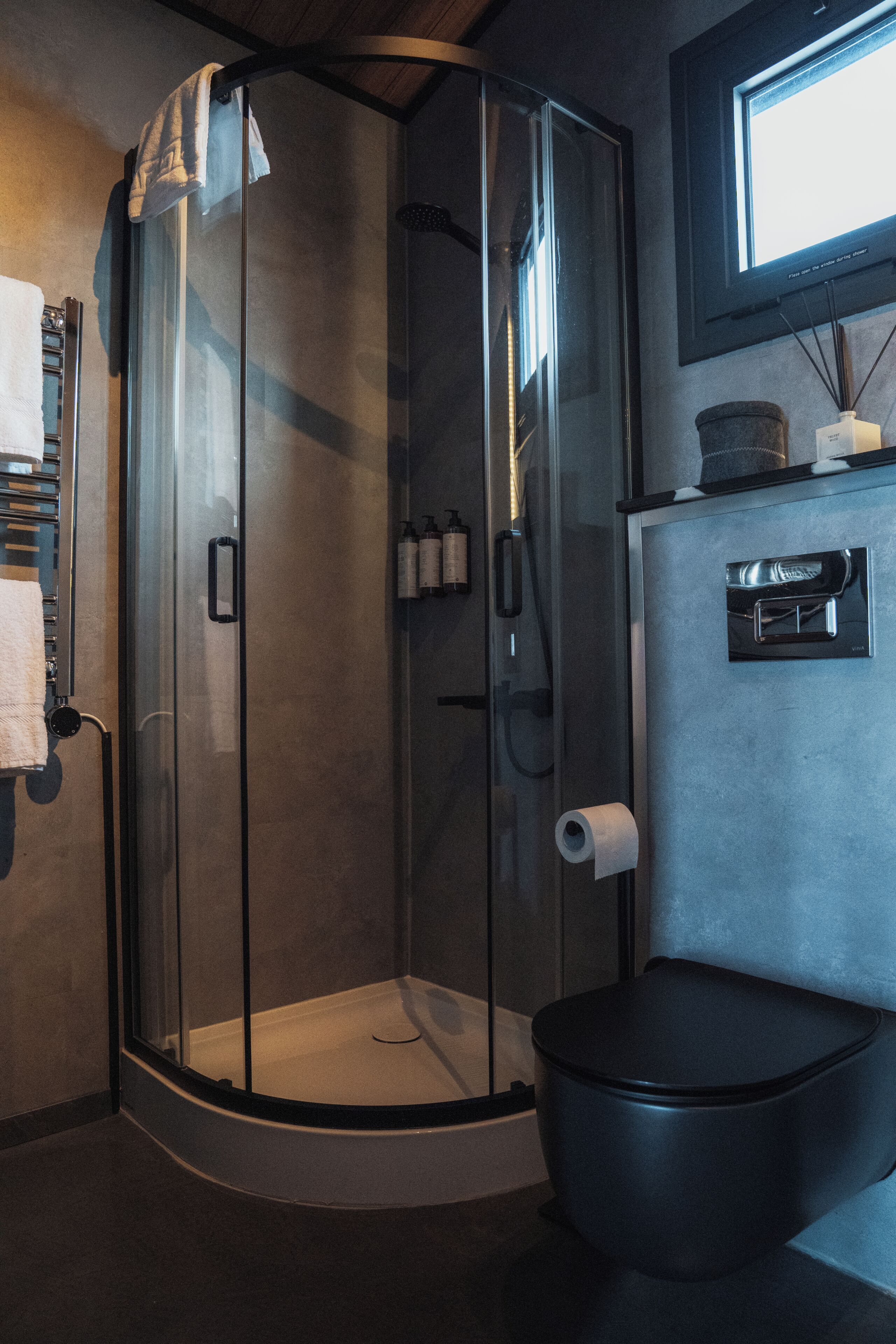 Une salle de bain moderne avec une douche à parois de verre, des toilettes et un lavabo équipé d’un distributeur de savon.