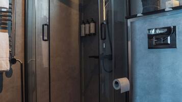 Une salle de bain moderne avec une douche à parois de verre, des toilettes et un lavabo équipé d’un distributeur de savon.