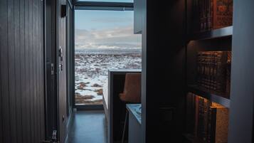 Un interior moderno con vista a la playa, una estantería y una maleta.