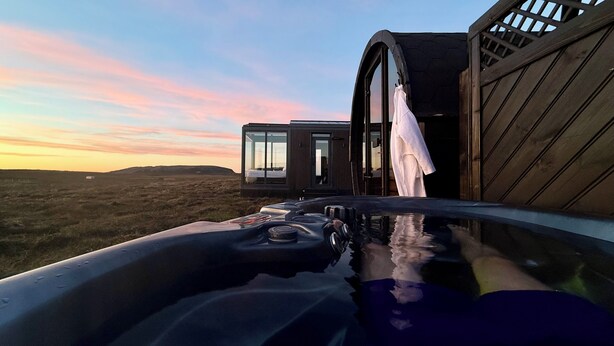 Un bâtiment moderne doté de grandes fenêtres et d’une façade en bois, vu depuis un jacuzzi.