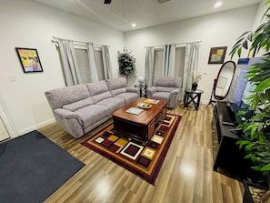 A living room with a sofa, armchair, coffee table, and a TV.