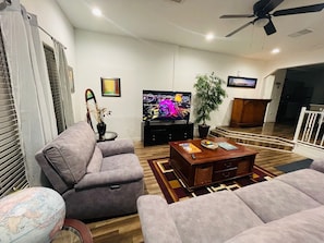 A living room with a television, sofa, coffee table, and a plant.