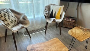 Moderni olohuone, jossa on kaksi nojatuolia, puinen sohvapöytä ja pieni sivupöytä.