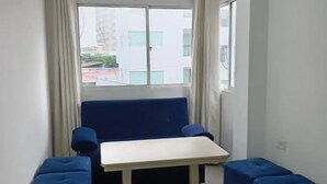 A small, modern room with a white table, blue ottomans, and a blue sofa.