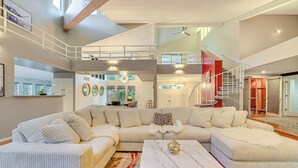 Un amplio salón con un sofá modular grande, una mesa de centro de mármol y un tapete estampado en rojo y beige.