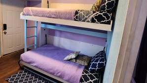 A bunk bed with a purple bedspread and patterned pillows.