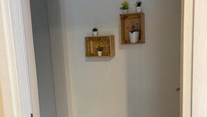 A hallway with wooden flooring and two wall-mounted shelves with potted plants.