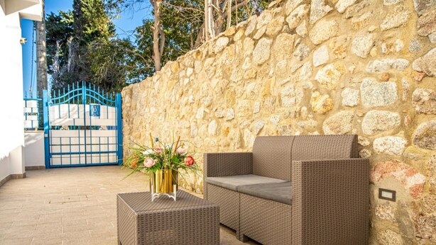 A patio area with wicker furniture and a stone wall.