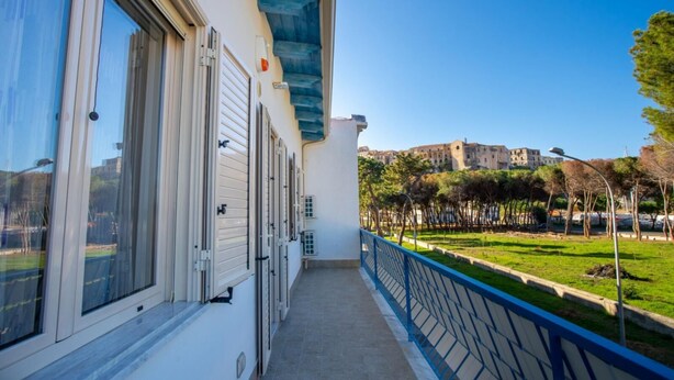 A balcony with a view of a park and a historic building in the background. - Apartment with Sea View (TROPEA)