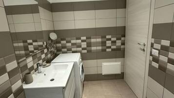 A compact bathroom with a sink, mirror, and washing machine.
