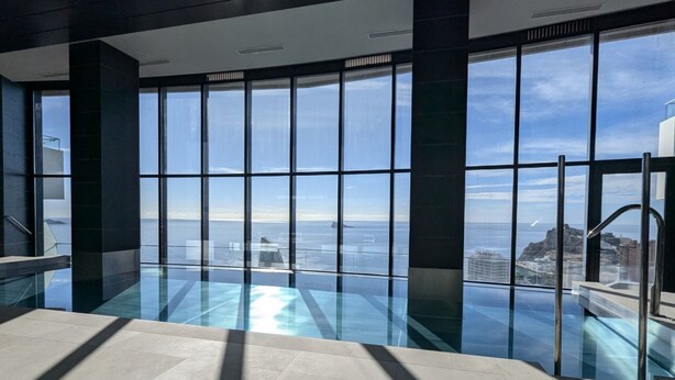 Piscina interior moderna con amplios ventanales que ofrecen vistas a la ciudad.