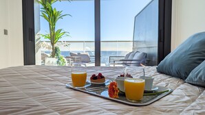 A bed with a tray of breakfast including fruit and orange juice, overlooking a balcony with a view of the sea. - SUNSET CLIFFS sweet apartment (Benidorm)