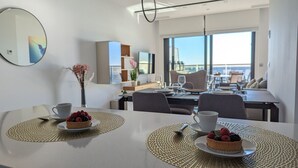A modern dining area with two round tables, each with a placemat and a plate of fruit. A vase with dried flowers is on the left table. - SUNSET CLIFFS sweet apartment (Benidorm)
