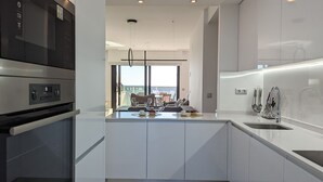 A modern kitchen with a central island, stainless steel appliances, and a view to the outside. - SUNSET CLIFFS sweet apartment (Benidorm)