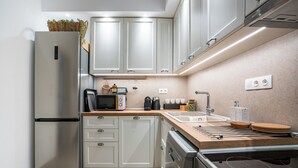 Une cuisine moderne dotée d’appareils électroménagers en acier inoxydable, de meubles blancs et d’un plan de travail en bois.