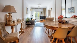 Un salon moderne avec une table à manger en bois, des sièges confortables, un canapé et un téléviseur.