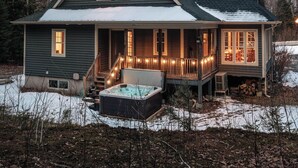 Una casa de dos pisos con un porche, un jacuzzi y vistas del paisaje circundante.