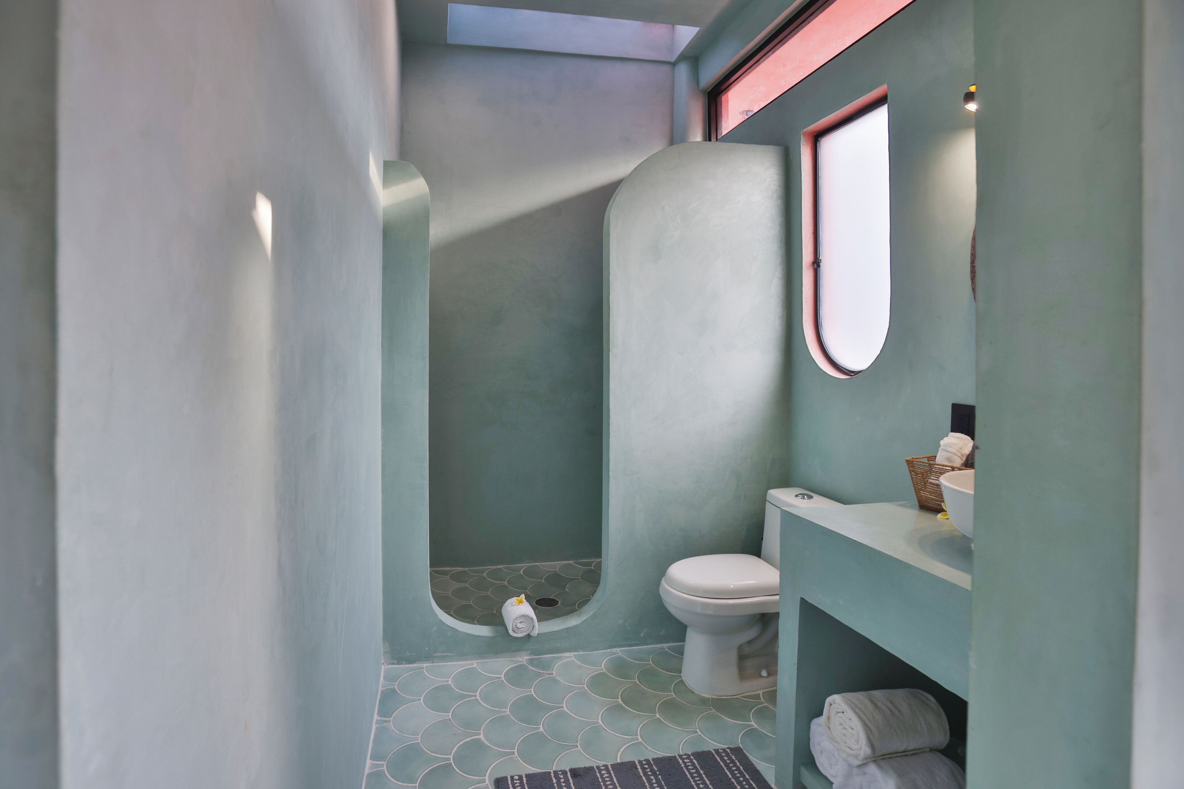 A bathroom with a toilet, a sink, a mirror, and a shower area.