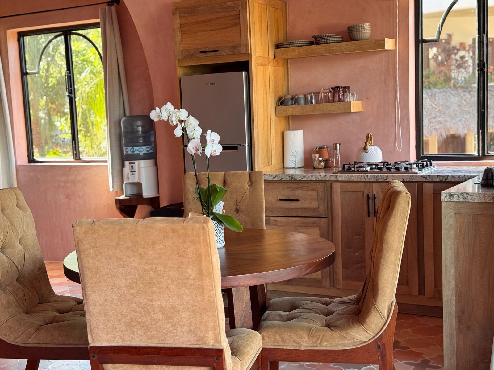 A modern kitchen with wooden cabinets, a round dining table, and chairs.