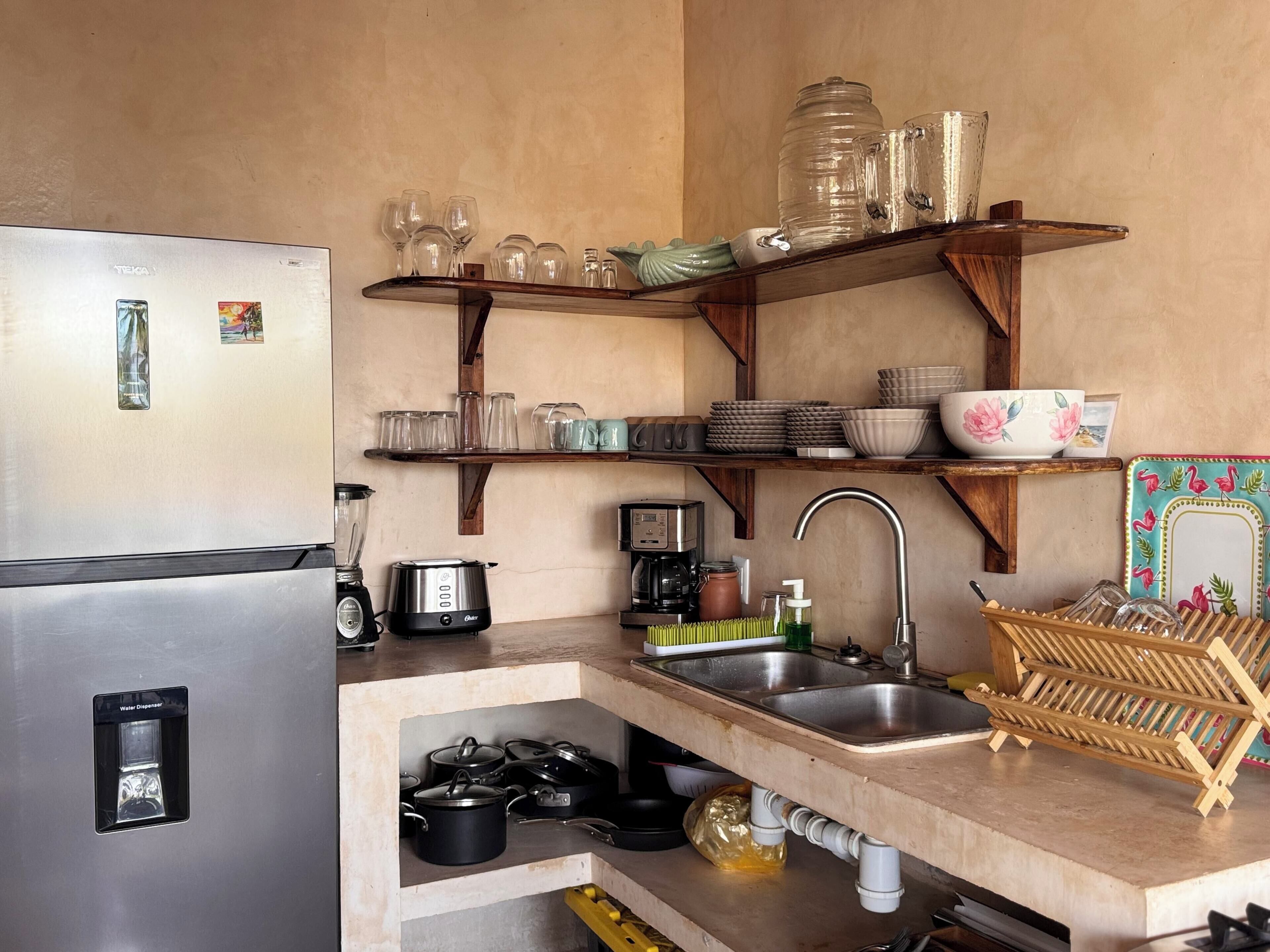 A compact kitchen with a refrigerator, coffee maker, and a sink.