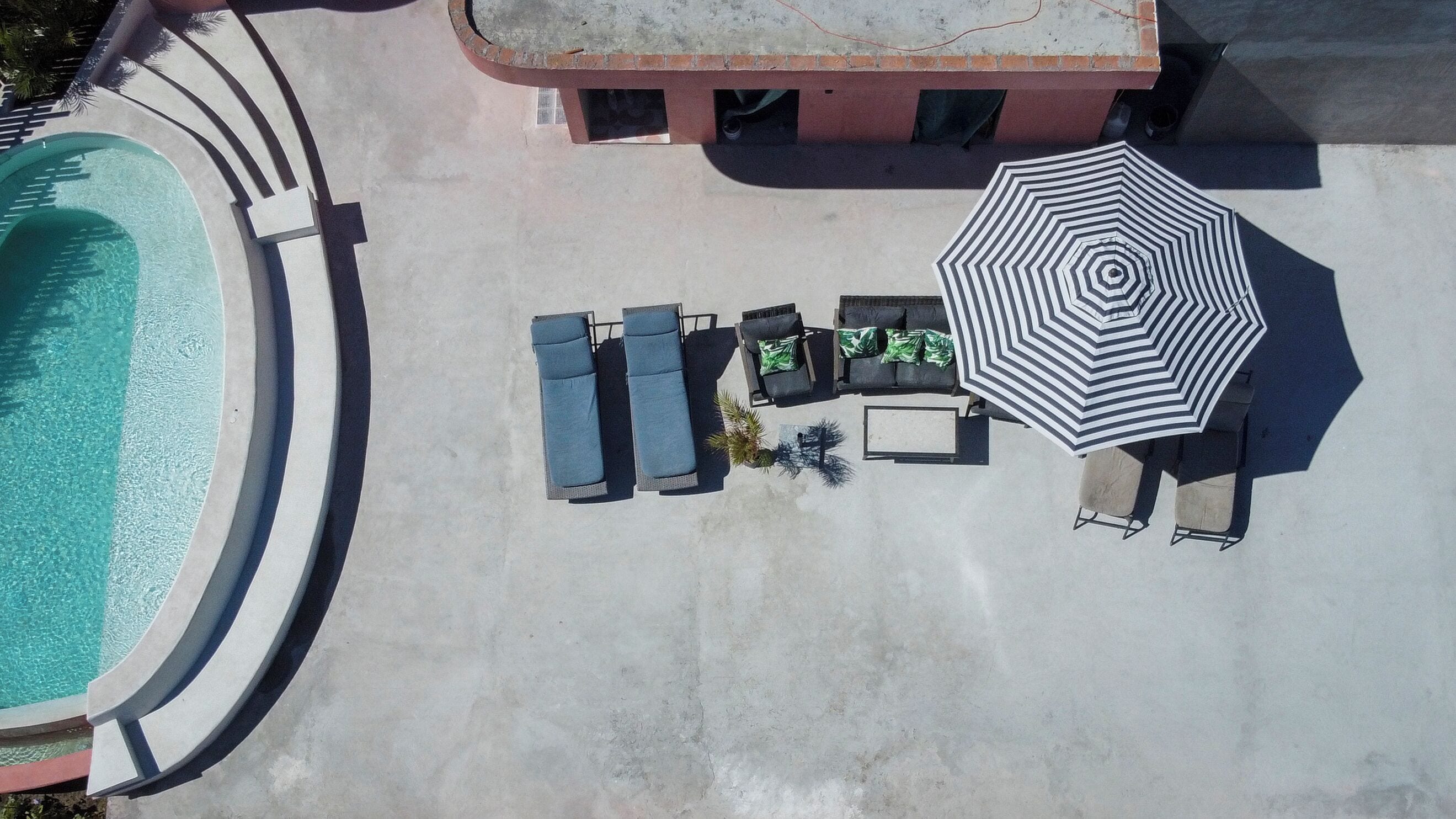 An aerial view of a pool area with lounge chairs and an umbrella.