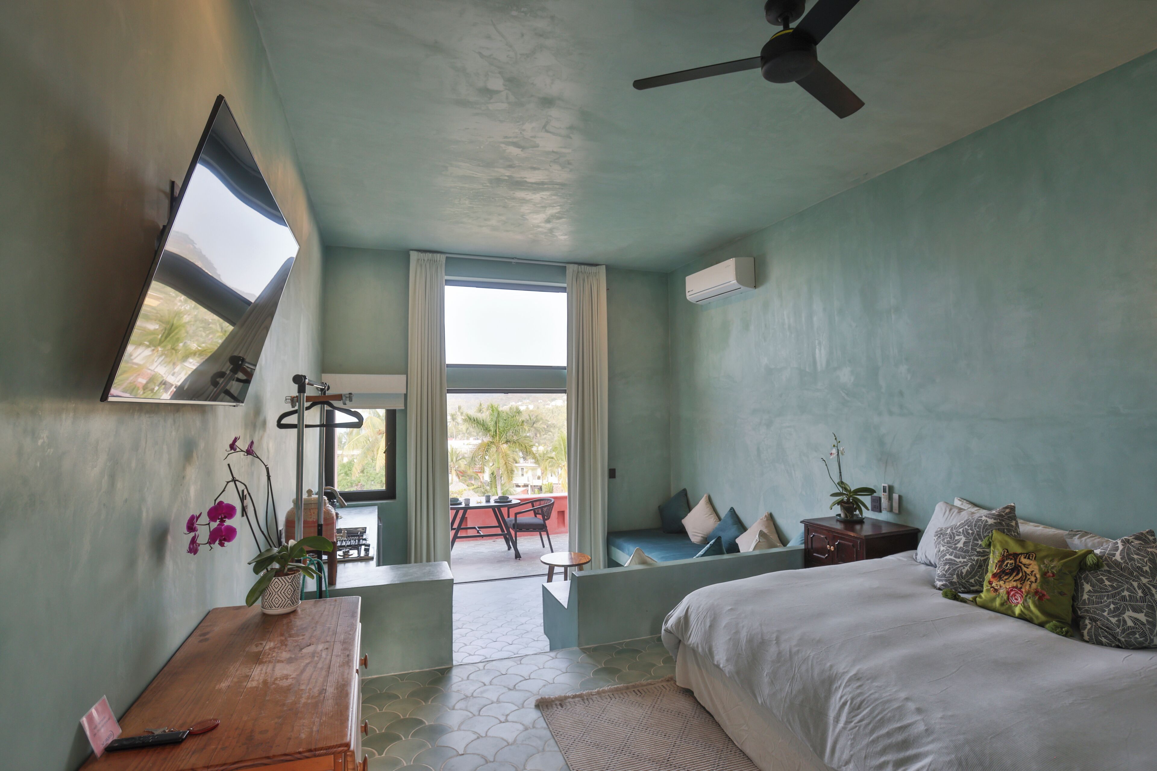 A bedroom with a bed, a desk, a chair, a window, and a ceiling fan.
