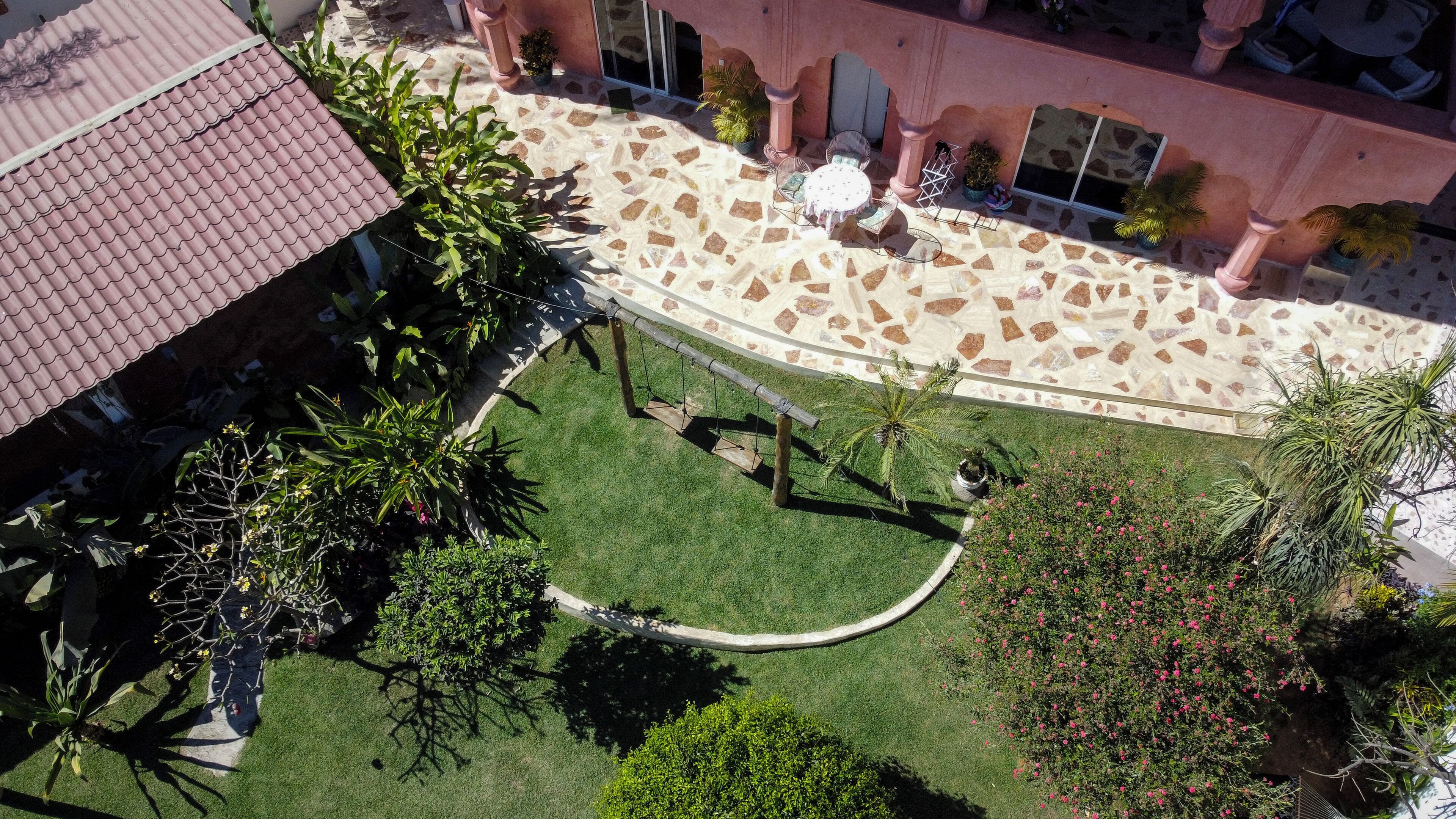 An aerial view of a courtyard with a stone patio, green lawn, and various potted plants.