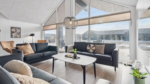 Un salón amplio con un ventanal grande, una lámpara moderna y vistas al exterior.