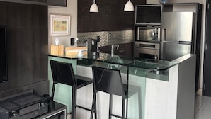 A modern kitchen with a central island, bar stools, pendant lighting, and a built-in oven. - NYC Residence Flat condominio (São Paulo)