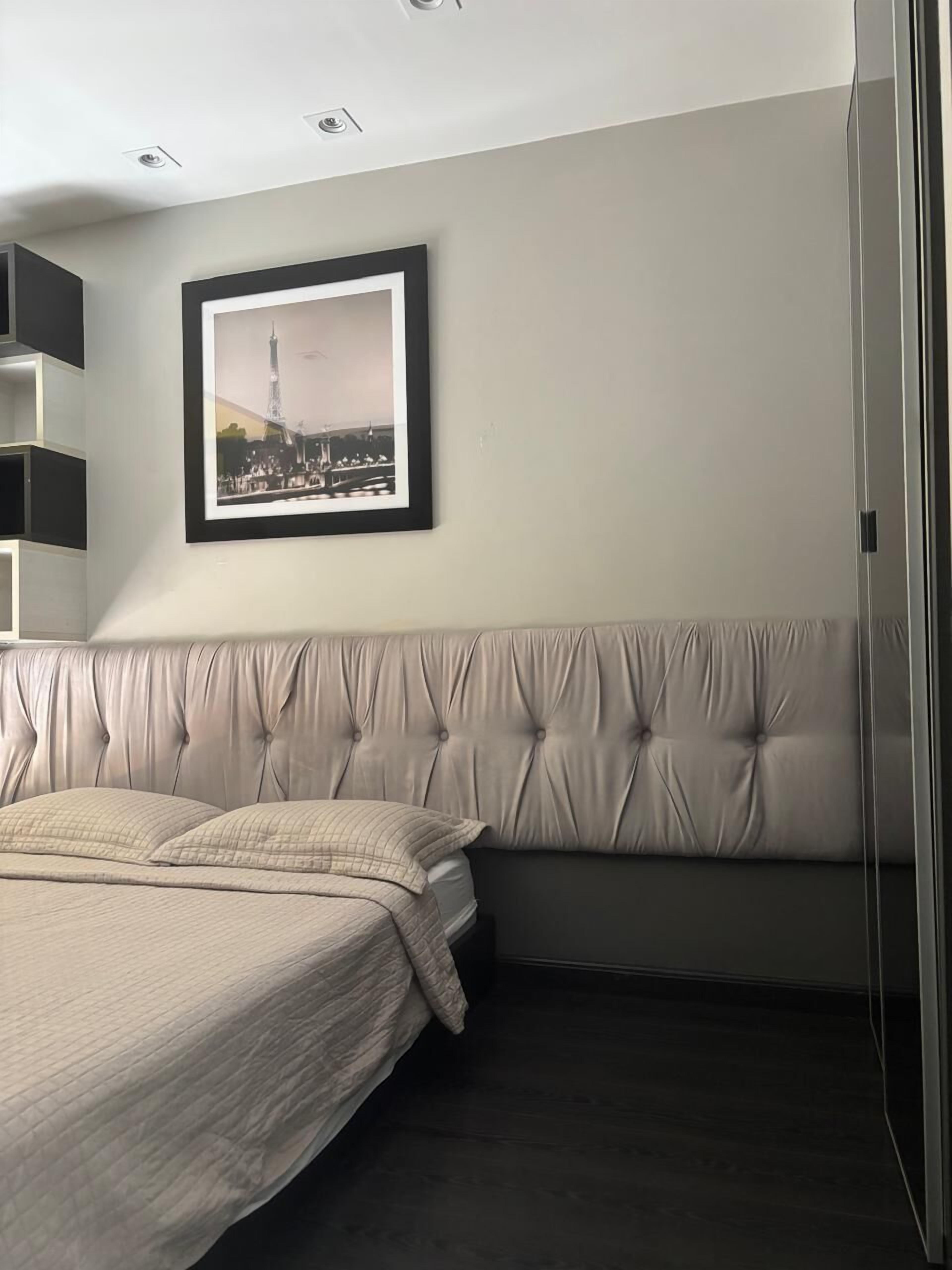 Ein Schlafzimmer mit Bett, Kopfstütze, gerahmtem Bild an der Wand und integrierten Regalen.