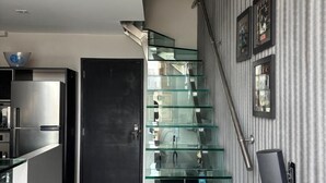 A modern kitchen with a stainless steel refrigerator, a glass staircase, and a black door. - NYC Residence Flat condominio (São Paulo)