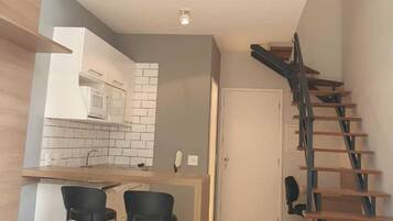 A modern loft apartment with a kitchen, dining area, and a staircase to the upper level.