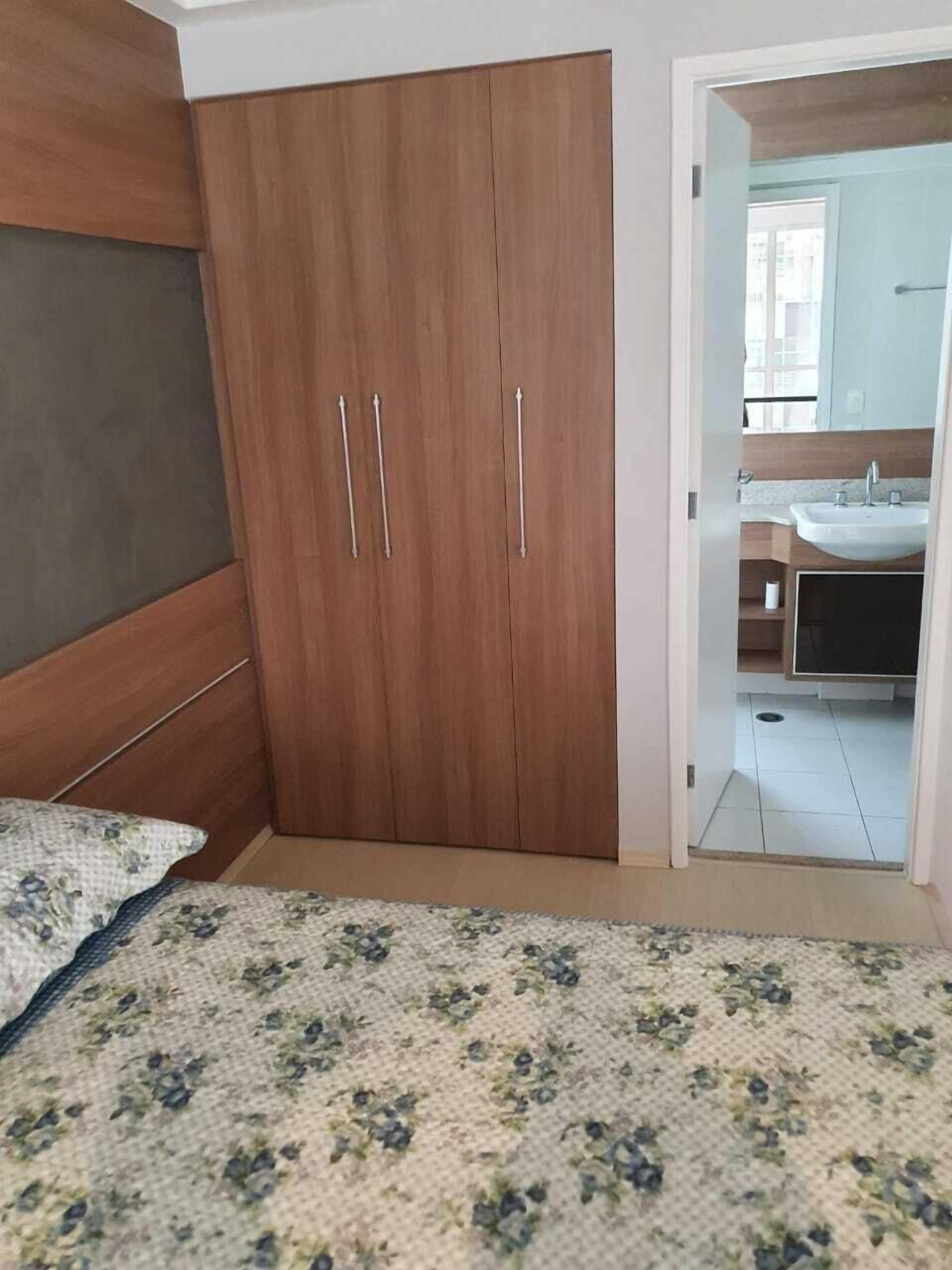 Une chambre à coucher avec un lit, une armoire et une salle de bain visible à travers une porte ouverte.