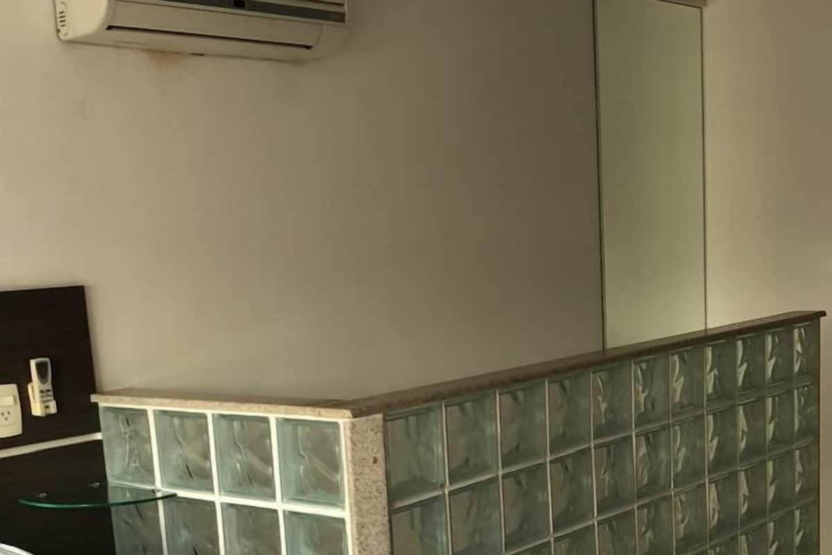 Ein Hotelzimmer mit Bett, einer Glasscheibe, einem Spiegel und einer Klimaanlage.