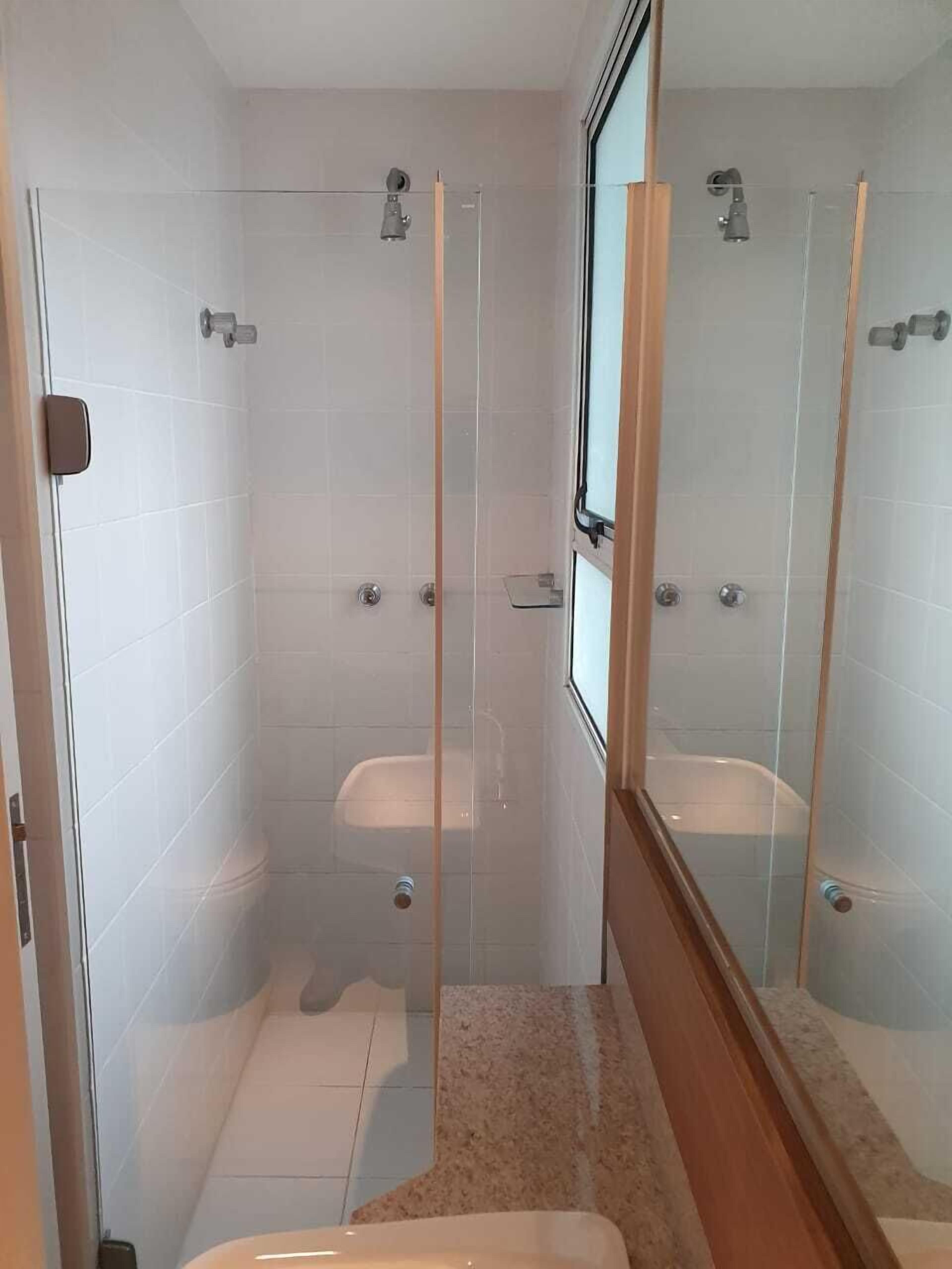 Ein modernes Badezimmer mit einer gläsernen Duschkabine, einer Toilette und einem Waschbecken.
