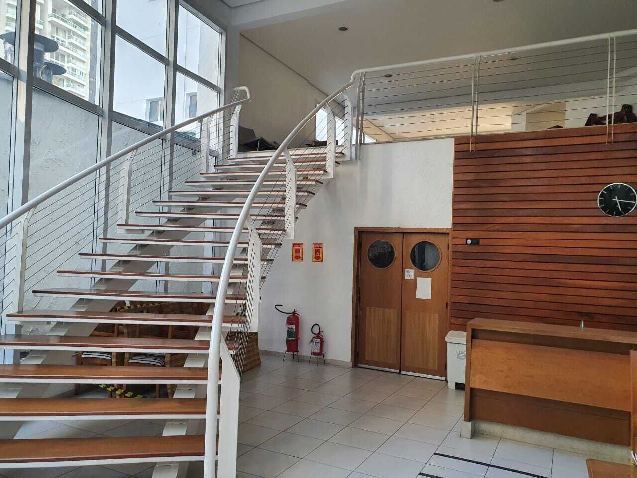 Una escalera de caracol con barandillas blancas, acabado de madera y un extintor cerca de la base.