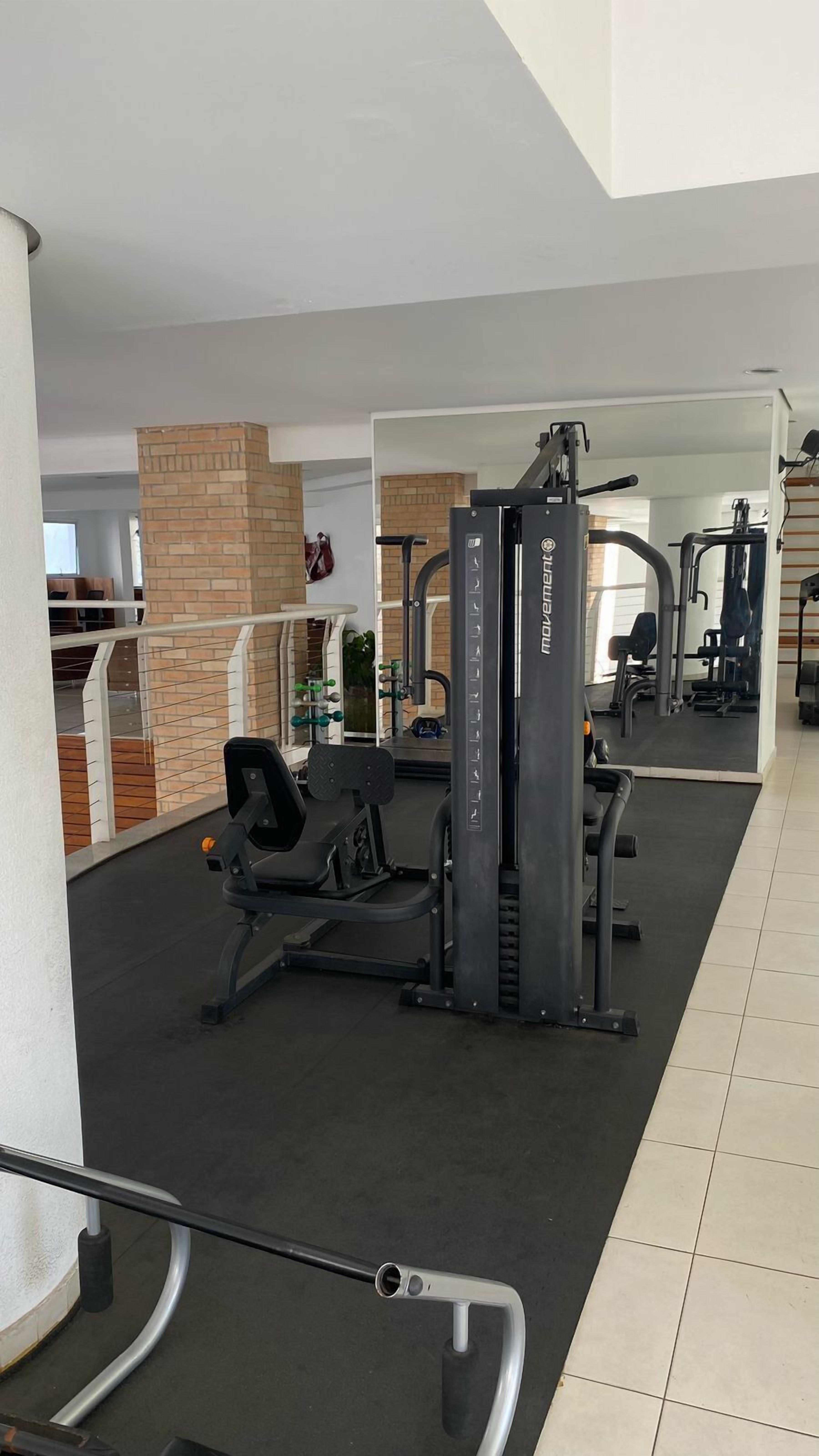 A gym with various exercise equipment, a mirror, and a brick wall.