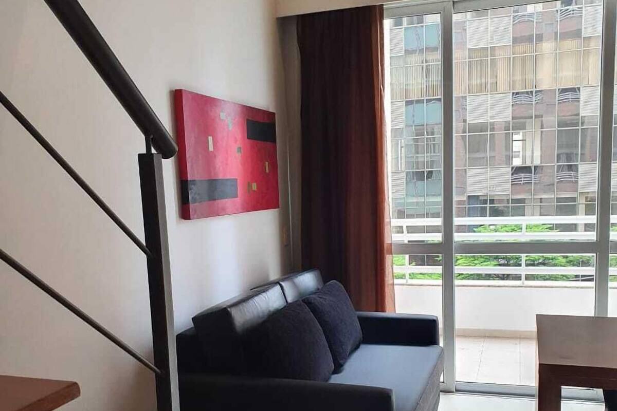 Ein modernes Wohnzimmer mit einer Couch, einer Treppe und Blick ins Freie.