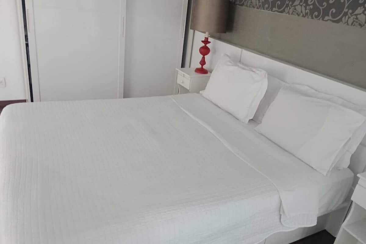 Ein ordentlich bezogenes Bett mit weißen Leinen in einem Hotelzimmer.