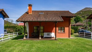 Una casa con techo de tejas, un porche cubierto y un jardín.