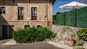 A stone building with a balcony, a green fence, and a potted plant. - Apartment 'La Breval' with Mountain View, Private Terrace and Private Garden (Alles)