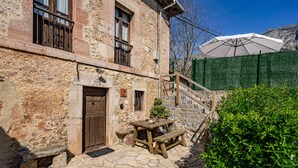 A stone building with a wooden door, a wooden bench, a picnic table, and a green hedge. - Apartment 'La Breval' with Mountain View, Private Terrace and Private Garden (Alles)