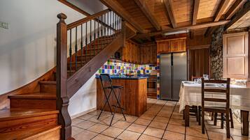 A wooden staircase, kitchen island, dining table, and chairs.