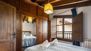 Una habitació amb panells de fusta, un llit amb mantell estampat, una làmpada penjant i una finestra amb vista.