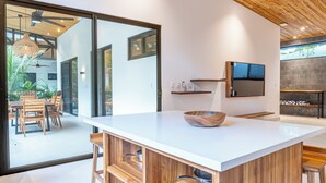 A modern kitchen with a large island, wooden shelves, and a built-in stove.