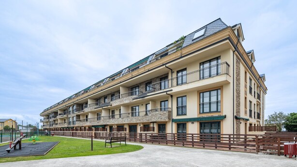 A multi-story residential building with balconies, a playground, and a paved walkway. - Apartment 'San Miguel Reinante' with Mountain Views, Pool and Wi-Fi (SAN MIGUEL DE REINANTE)