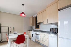 Una cocina compacta equipada con lavadora, horno, microondas y refrigerador.
