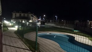 A nighttime view of a swimming pool area with a fence, a pathway, and buildings in the background. - Apartment 'San Miguel Reinante' with Mountain Views, Pool and Wi-Fi (SAN MIGUEL DE REINANTE)