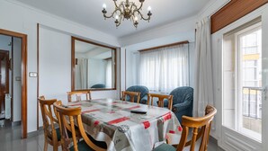 Un comedor con una mesa, sillas, una araña y un espejo grande.